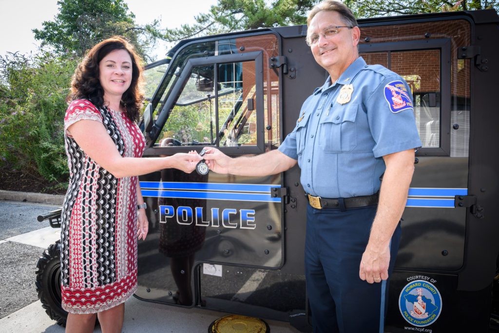 A woman and man in front of a police truck.