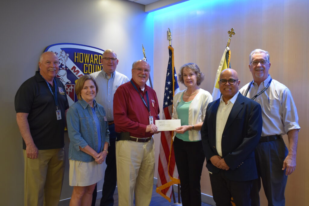 A group of people standing around a man holding a check.