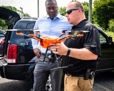 Two men standing in front of a car with an drone, exploring new initiatives.