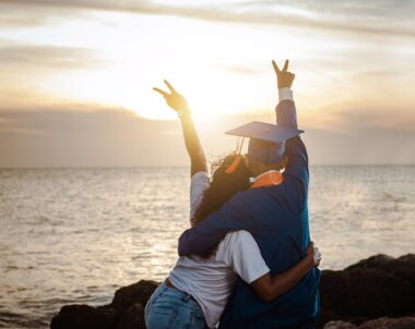 Two people hugging on the beach at sunset.