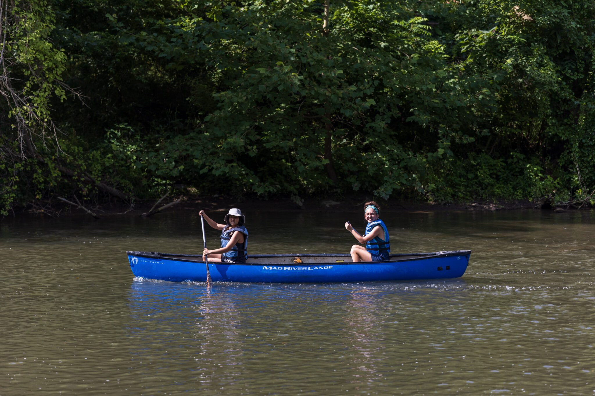 Two people in a blue canoe participate in the P.L.E.D.G.E. Leadership Program.