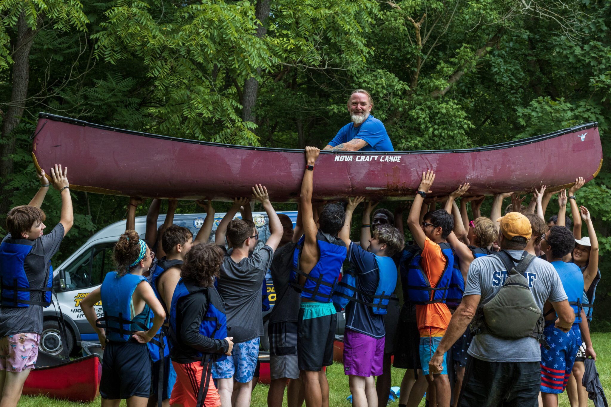 A man holds up a canoe at the P.L.E.D.G.E. Leadership Program.