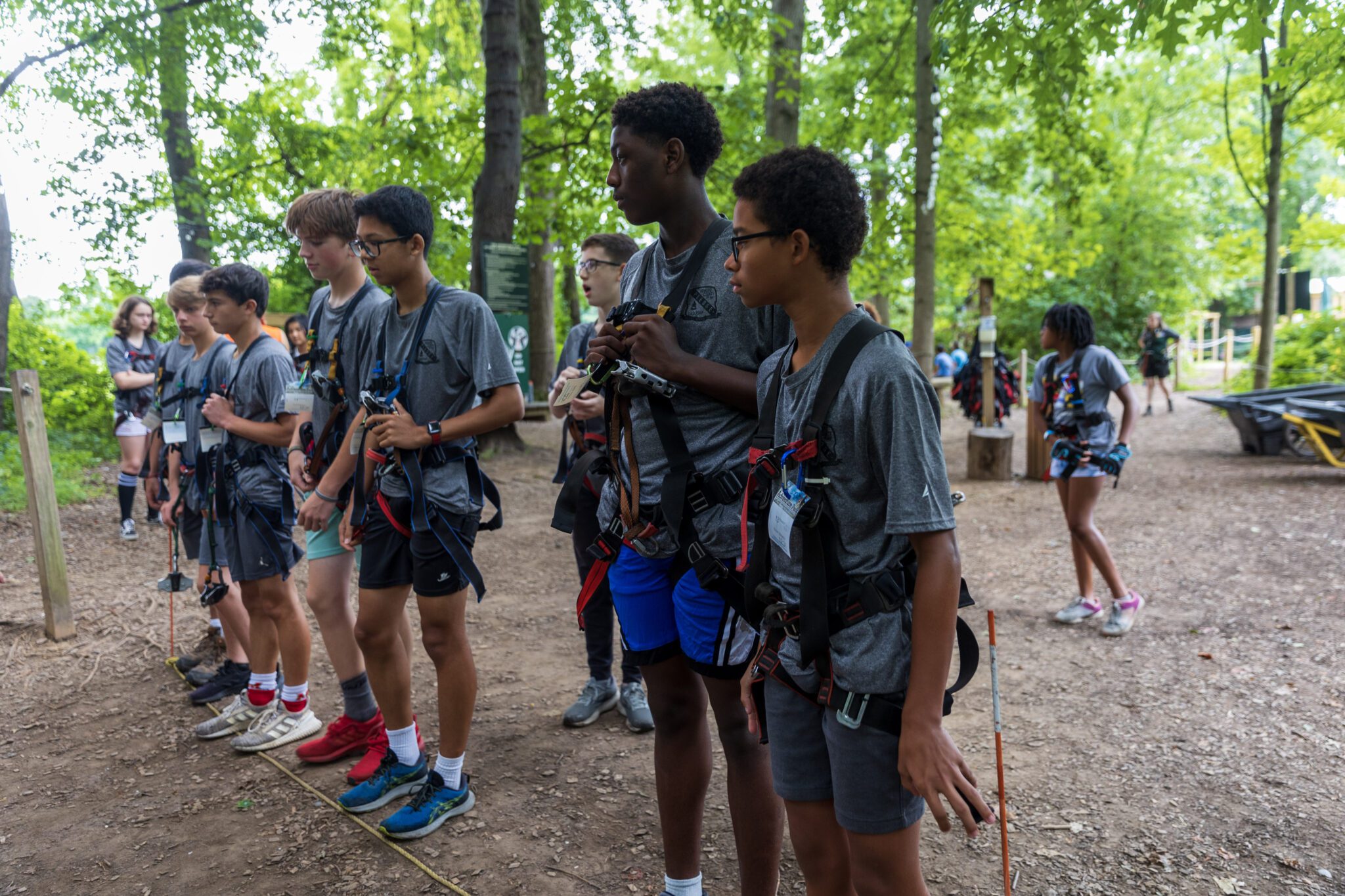 A group of young people participating in the P.L.E.D.G.E. Leadership Program standing in a wooded area.