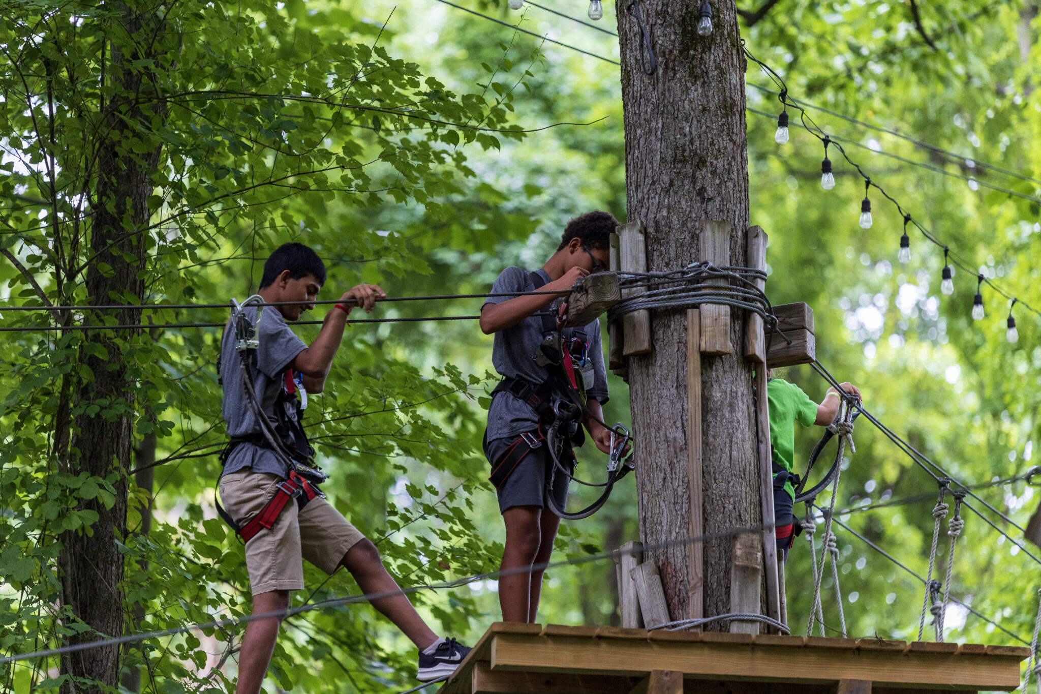 A group of people participating in the P.L.E.D.G.E. Leadership Program on a zip line in the woods.