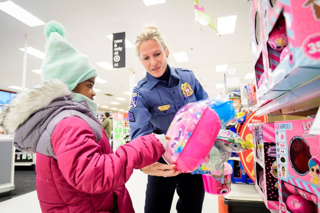 Shop With A Cop program where a police officer handing a child a toy in a store.