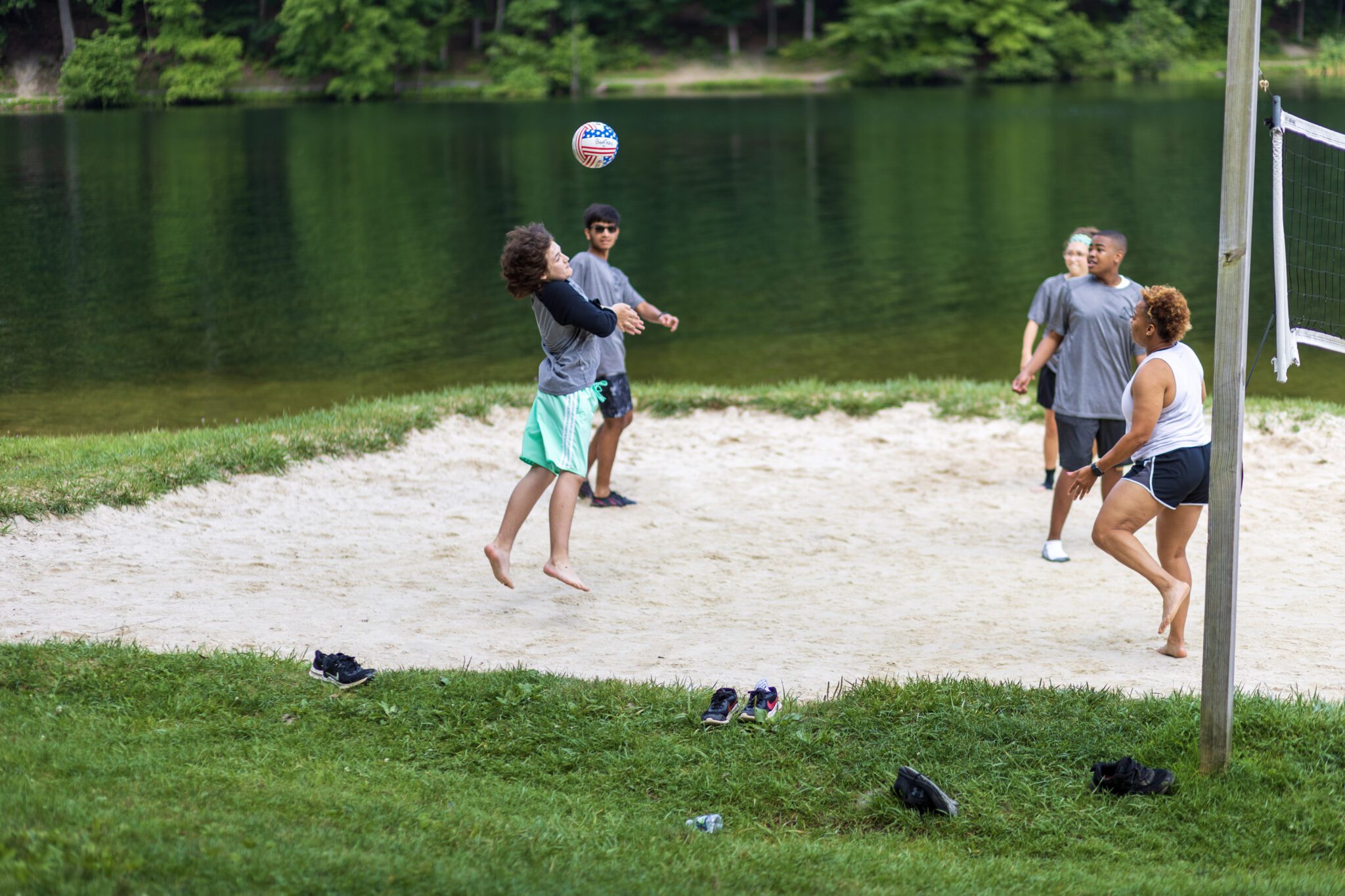 A group of people participating in the P.L.E.D.G.E. Leadership Program playing volleyball in the sand.