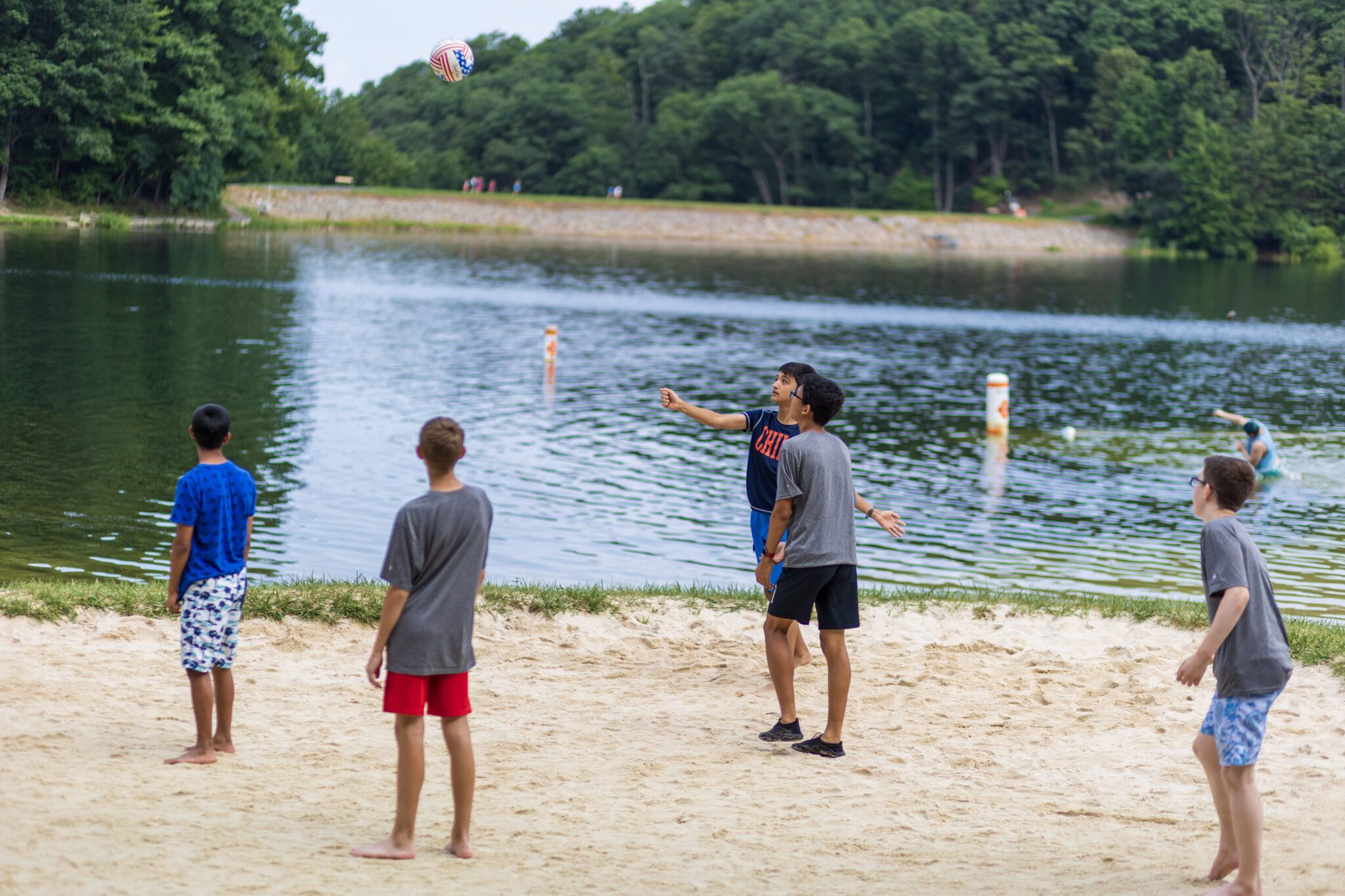 A group of boys participating in the P.L.E.D.G.E. Leadership Program playing a game of frisbee in the sand.