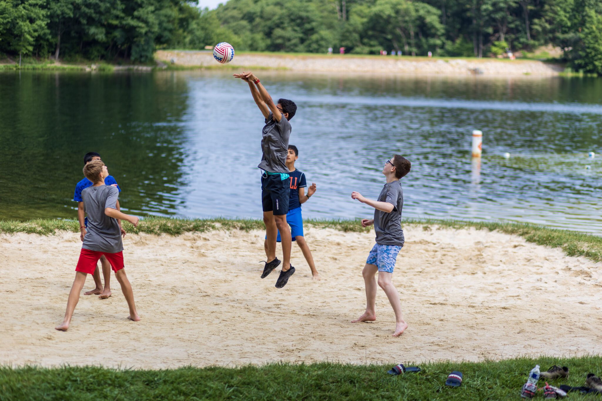 A group of boys participating in the P.L.E.D.G.E. Leadership Program playing a game of frisbee in the sand.