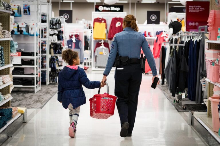 A woman and a child participating in the Shop With A Cop program, walking down a store aisle.