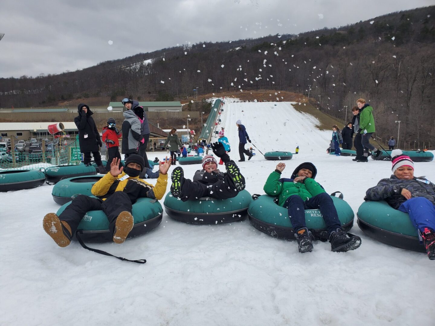 A group of people on tubes participating in the P.L.E.D.G.E. Leadership Program on a snowy slope.