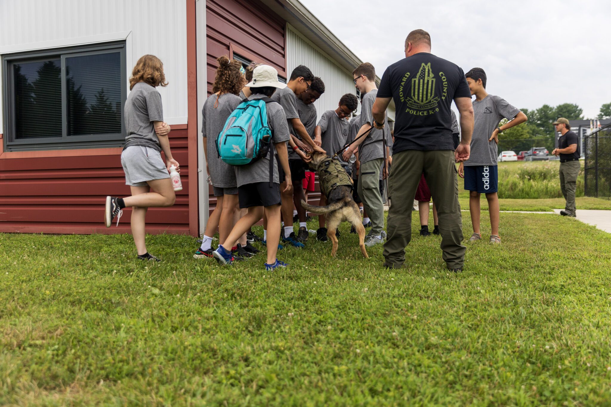 A group of people participating in the P.L.E.D.G.E. Leadership Program standing in front of a building with a dog.