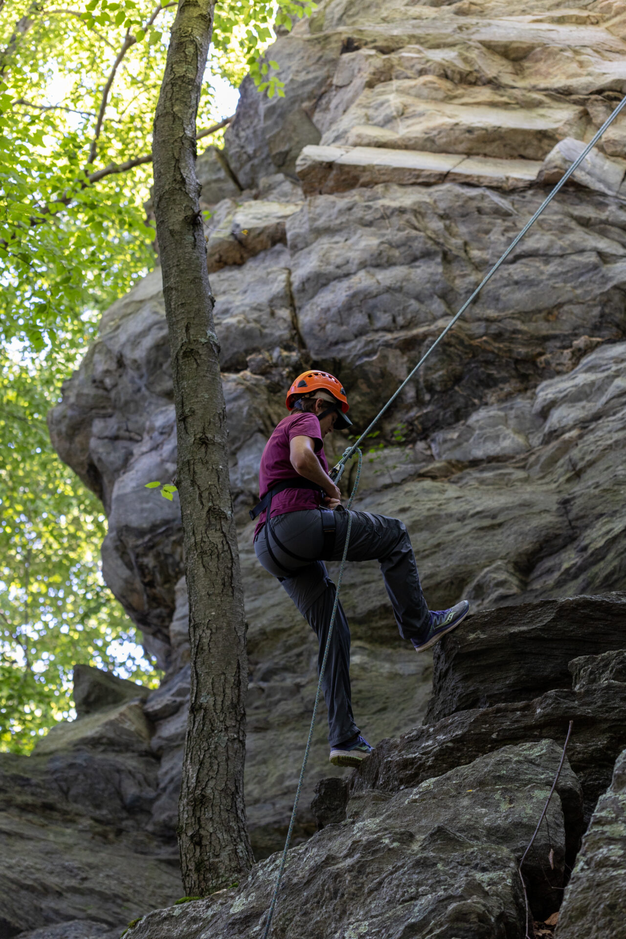 A person on a rocky cliff, utilizing BearTrax to ascend.