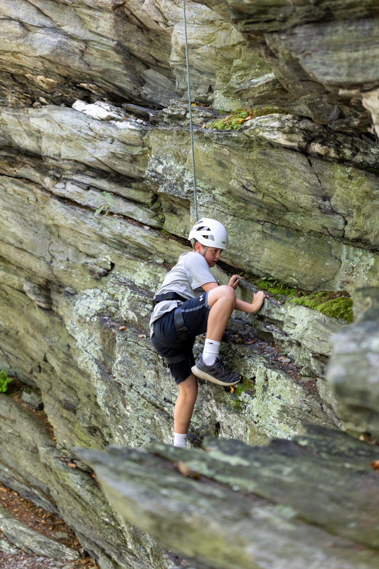 A young boy fearlessly scaling a rocky cliff, leaving behind his BearTrax.