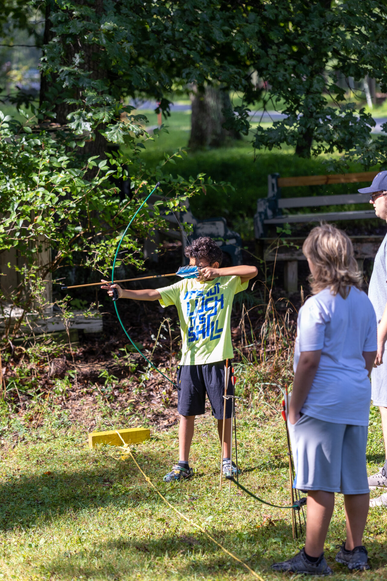 A group of people are playing archery in a park, using the BearTrax equipment.