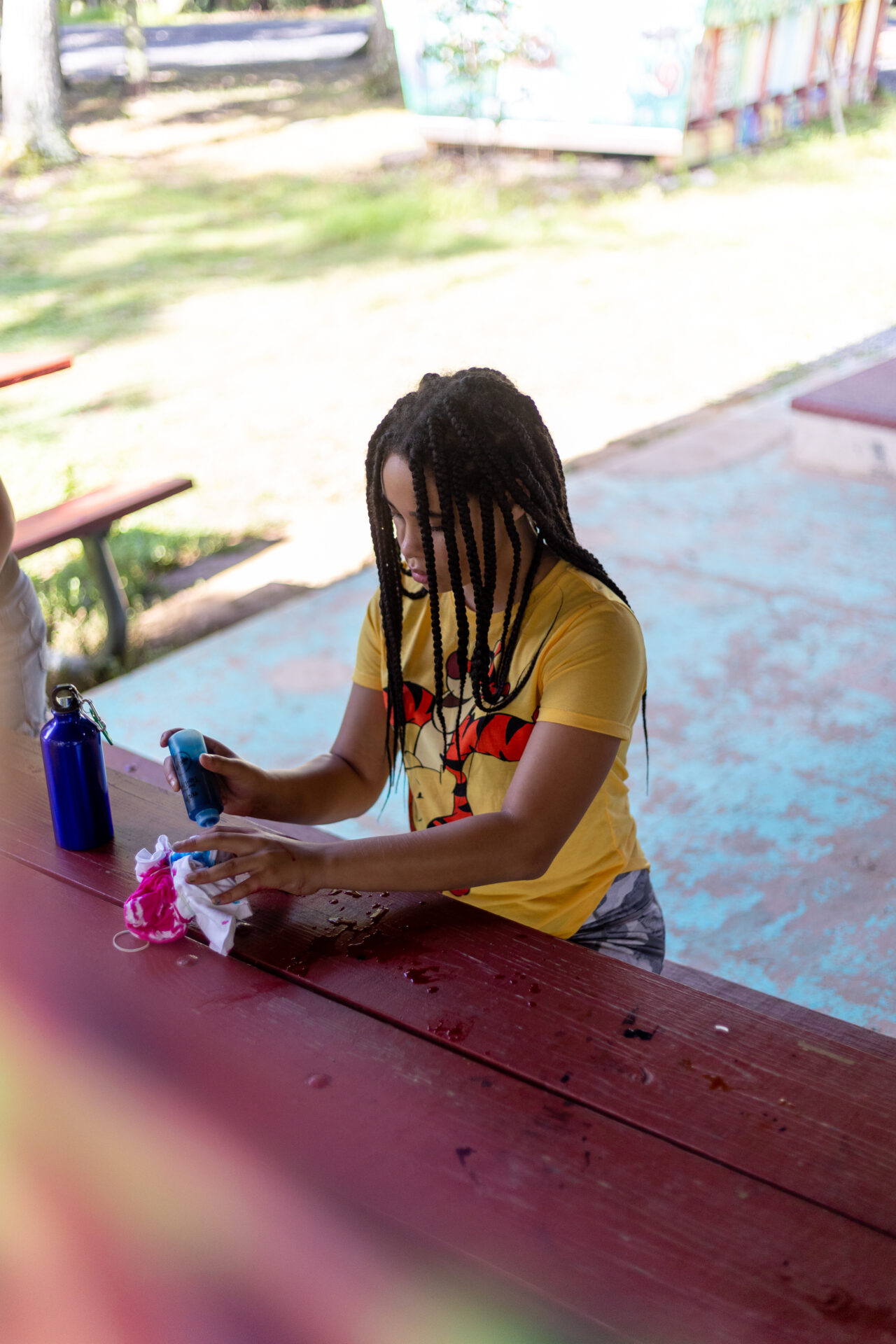 A woman with dreadlocks sitting at a picnic table enjoying the serene BearTrax surroundings.