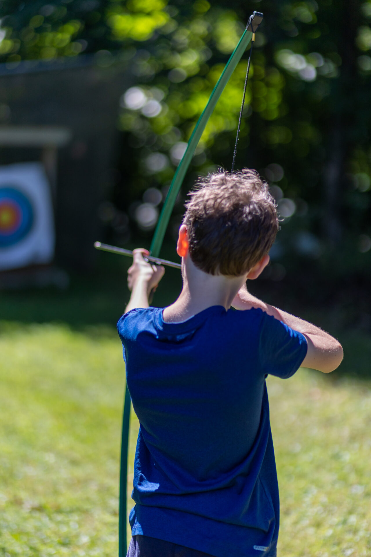 A young boy expertly aims his BowTrax at an archery target.