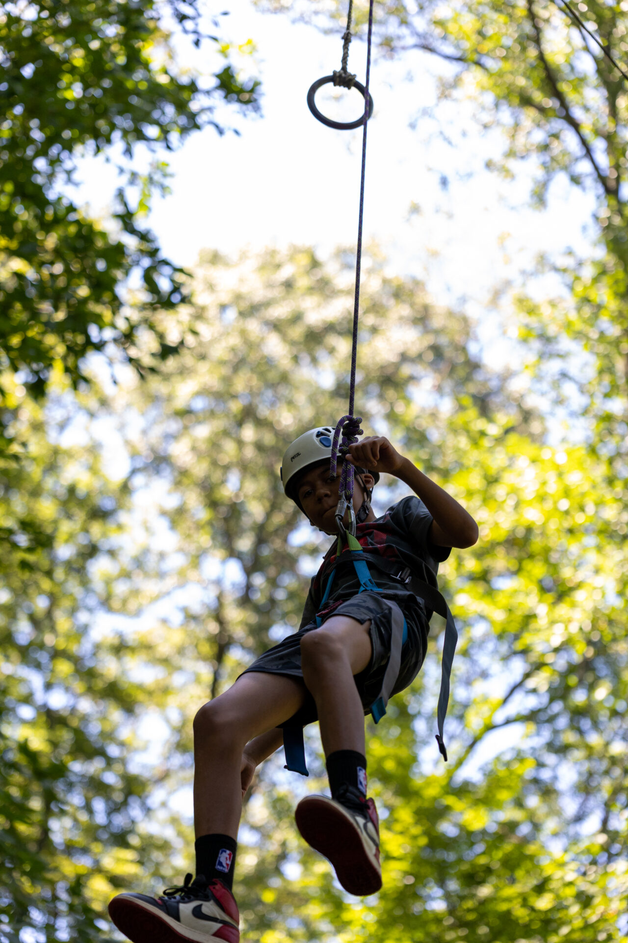 A thrilling BearTrax adventure where a person soars through the air on a zip line, embracing the excitement and adrenaline rush of being suspended high above the ground.