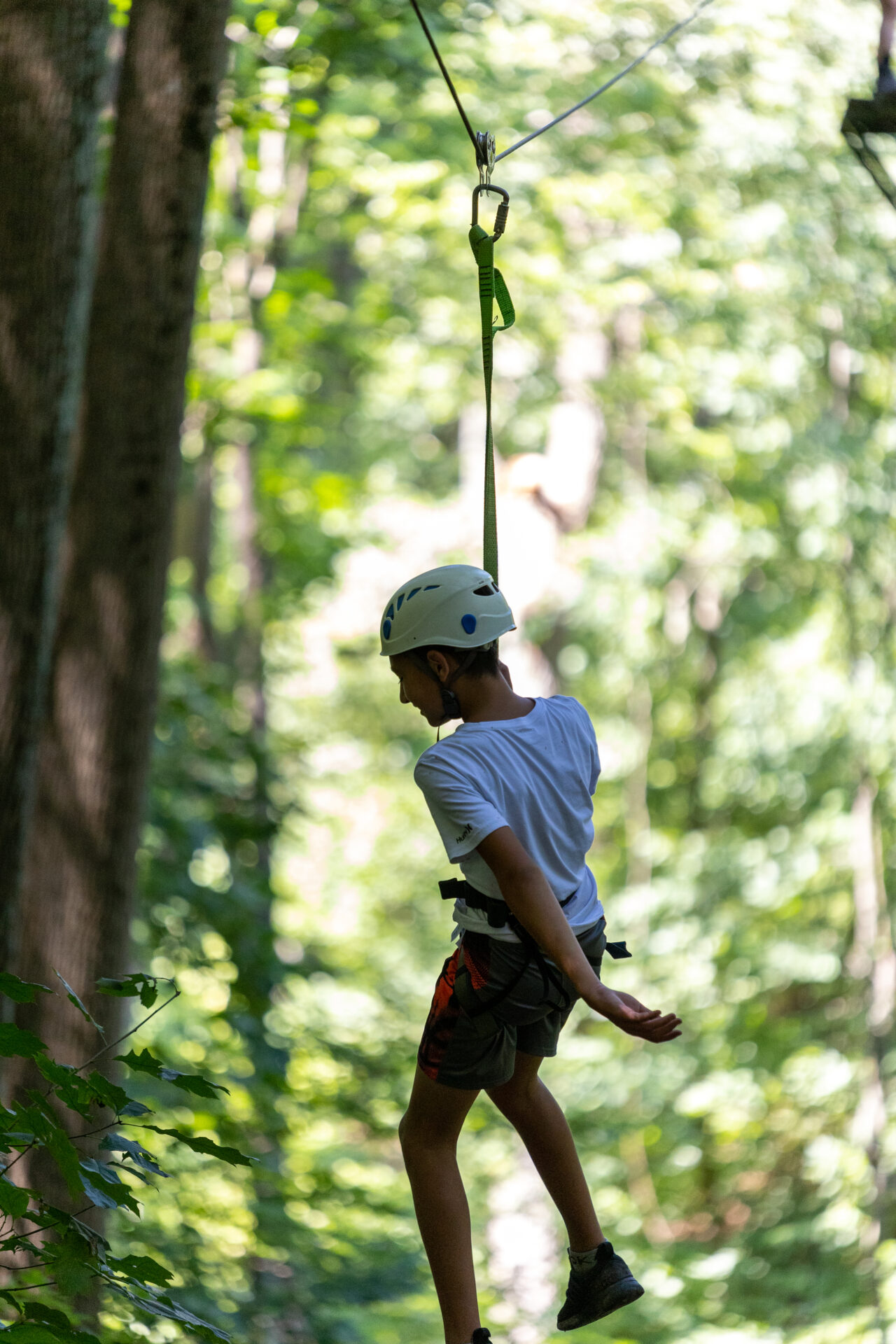 A boy on a BearTrax zip line in the woods.