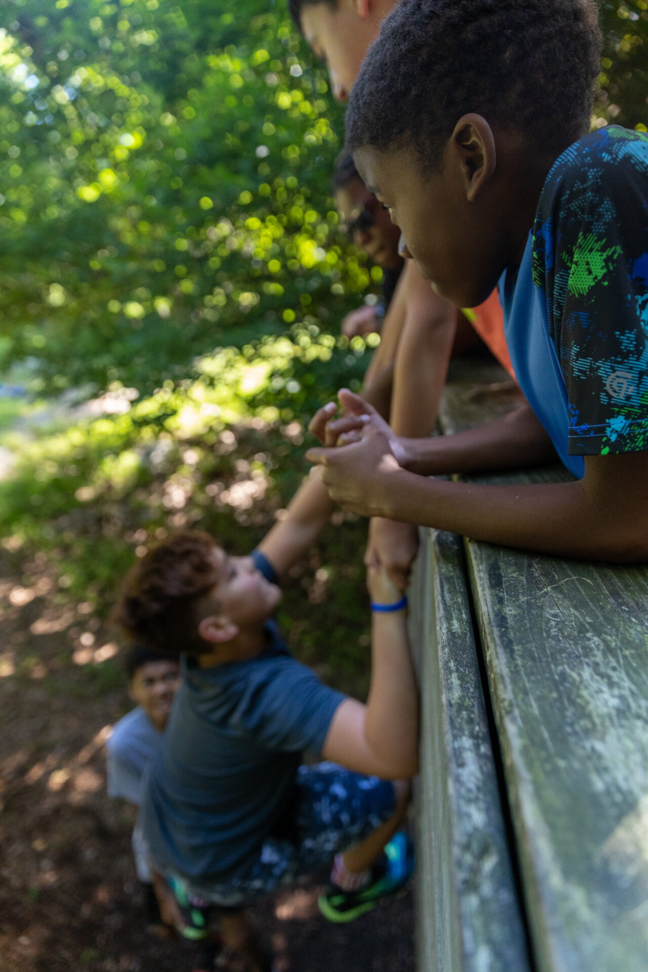 A group of children are holding hands on a BearTrax trail in the woods.