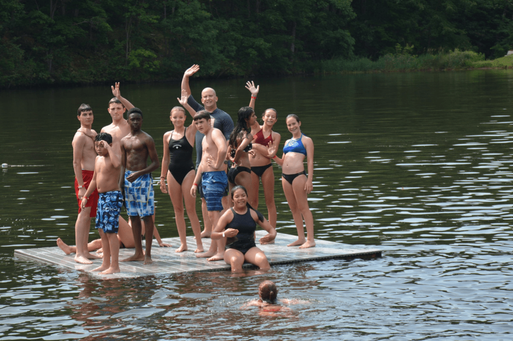 A group of individuals participating in the P.L.E.D.G.E. Leadership Program on a floating platform.