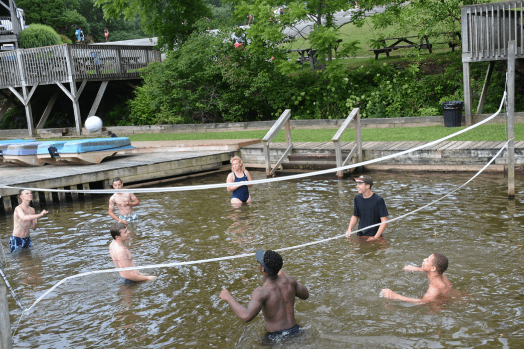 A group of people participating in the P.L.E.D.G.E. Leadership Program, enjoying a game of volleyball in the water.