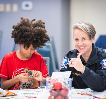 A police officer and a child sitting at a table at the HoCo Kids Holiday Party.