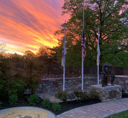 The HCPD Memorial Garden features a beautiful sunset backdrop, adorned with flags to honor fallen heroes.
