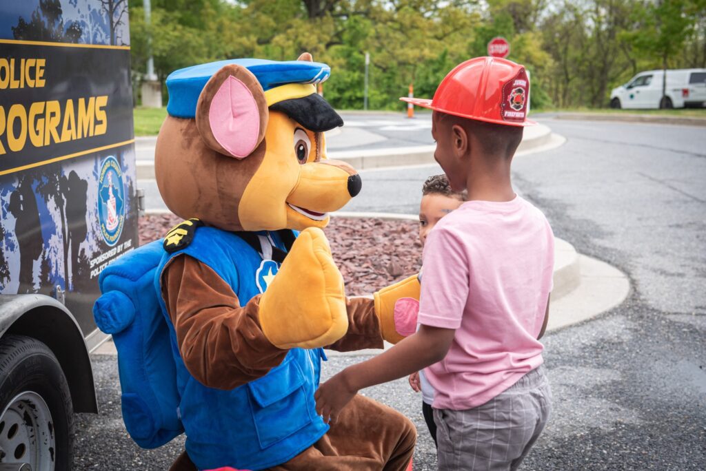 A boy is shaking hands with a National Night Out mascot.