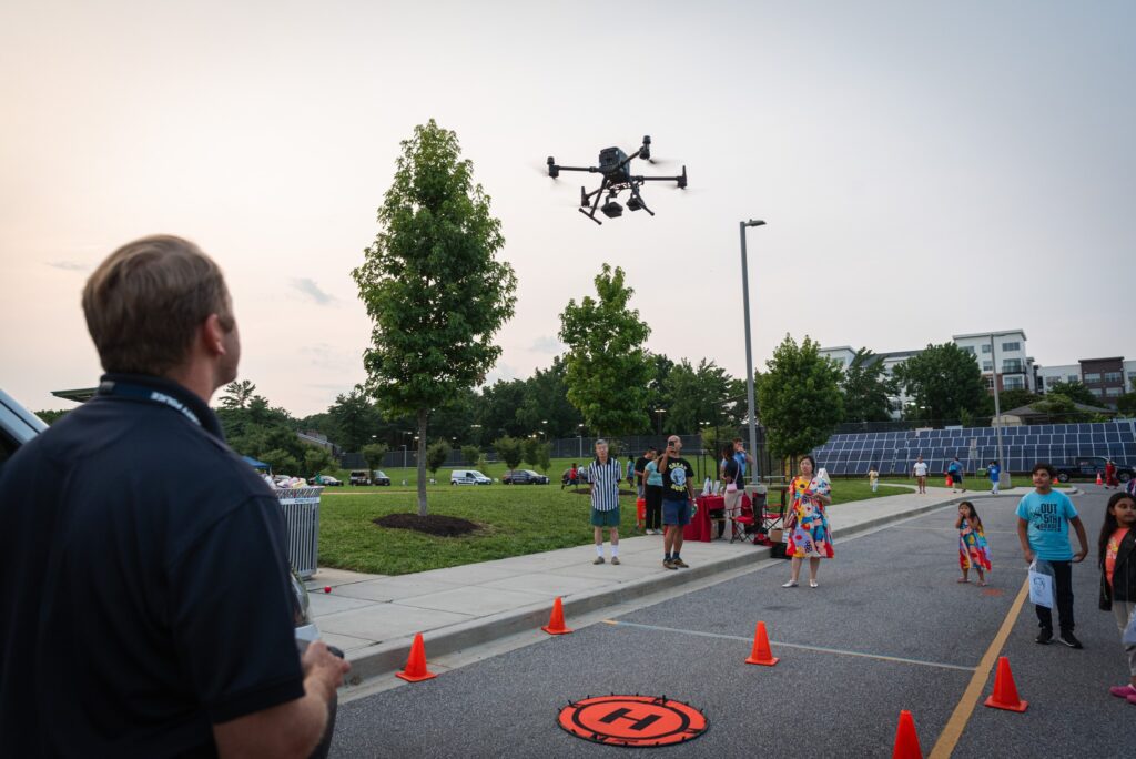 A group of people observing a drone soar through the sky, utilizing HCPD Equipment.
