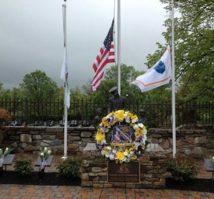 A wreath with flags in front of the HCPD Memorial Garden, which is marked by a stone wall.