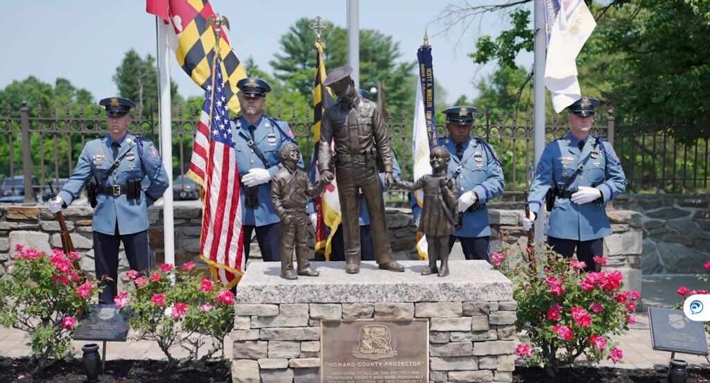 A HCPD Memorial Garden with a statue of a police officer in front of a flag.