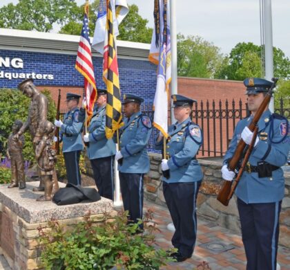 A group of police officers stand in front of the HCPD Memorial Garden statue.