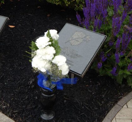 Two plaques with flowers in front of them located in the HCPD Memorial Garden.