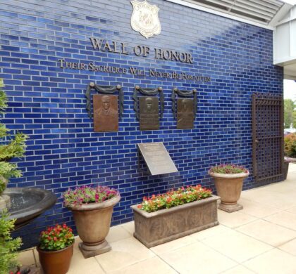 A blue brick building with a plaque on it, located within the HCPD Memorial Garden.