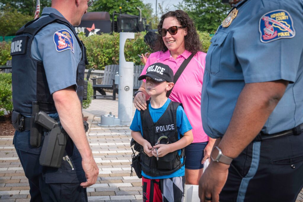 A boy is smiling for the camera while two police officers look on.