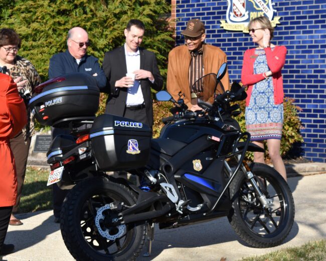 A group of people standing around a motorcycle.