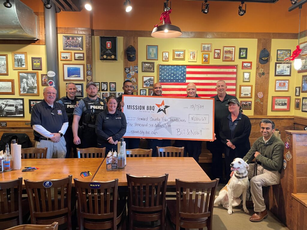 Group presenting a large check in a cozy restaurant setting.