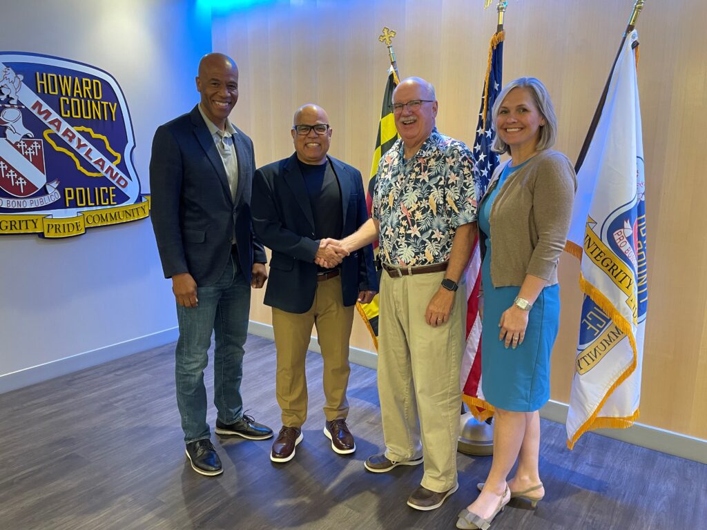 Four people standing together smiling in a well-lit room.
