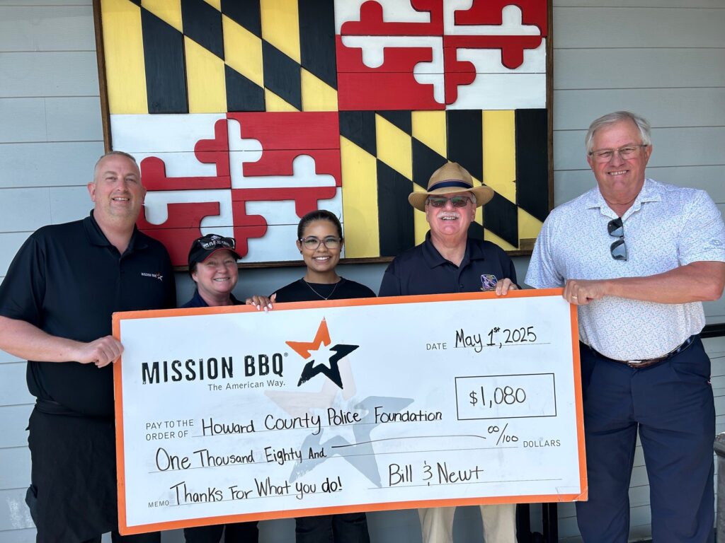 Four people hold a large check for $11,600 from Mission BBQ to Anne Arundel County Fire Department.