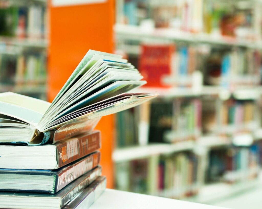 An open book atop a stack in a library.