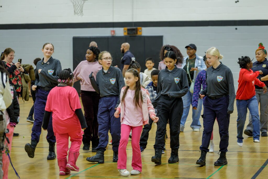 Children and adults interacting in a gymnasium setting.